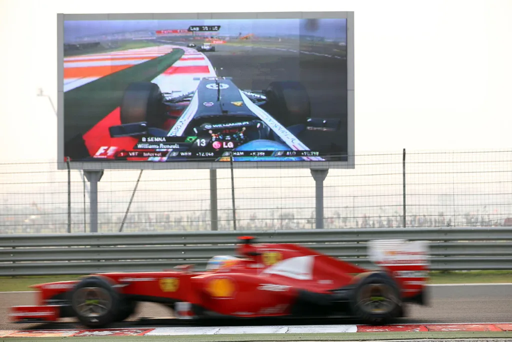 Spanish Formula One driver Fernando Alonso of Ferrari steers his car in front of a video screen during the Formula One Grand Prix of India at the race track Buddh International Circuit, Greater Noida, India, 28 October 2012.