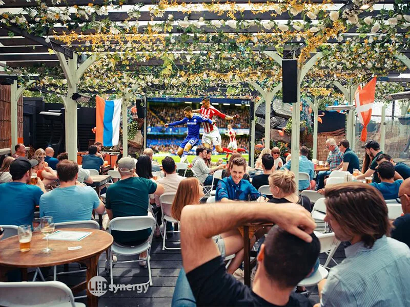 People watching Chelsea FC playing football on large outdoor pub garden screen